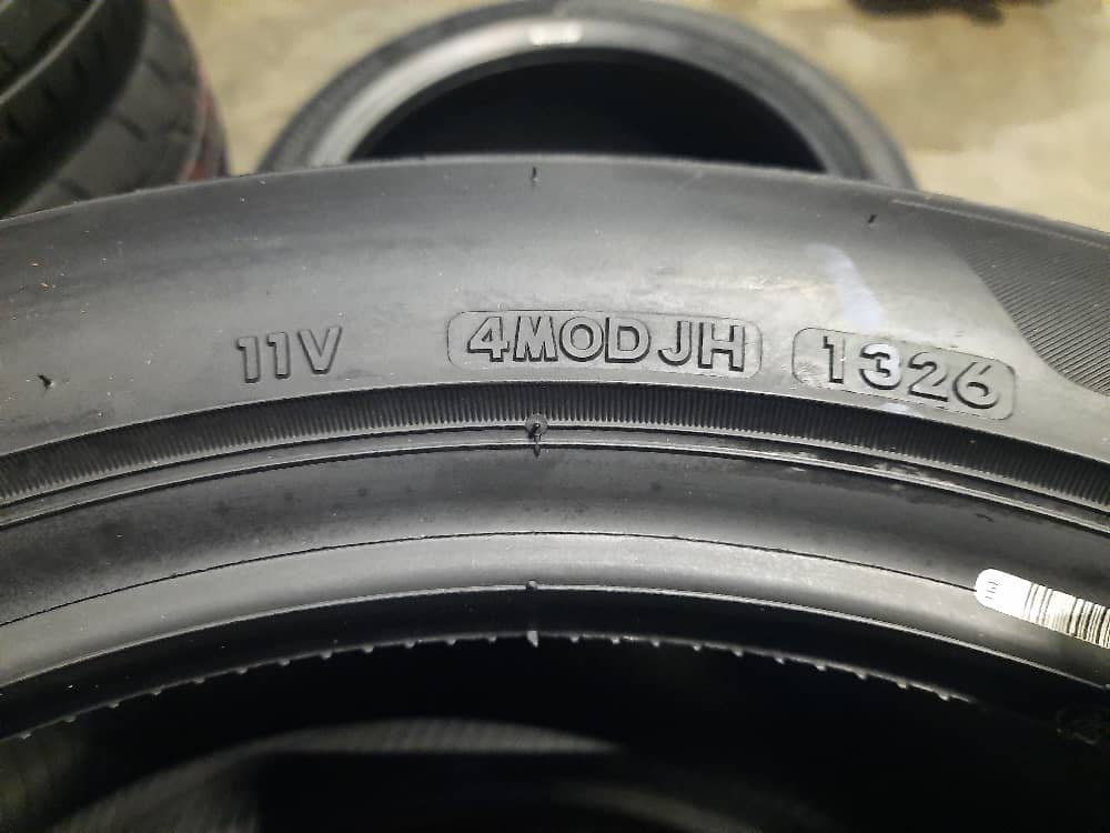 Photo of a tyre sidewall showing the full DOT identifier 11V4MODJH1326 (date code 1326 means week 13 of 2026)